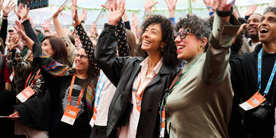 Smiling MozFest attendees with festival badges raise their hands and cheer together.