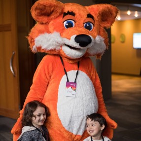 Two children posing for a picture with the Firefox mascot