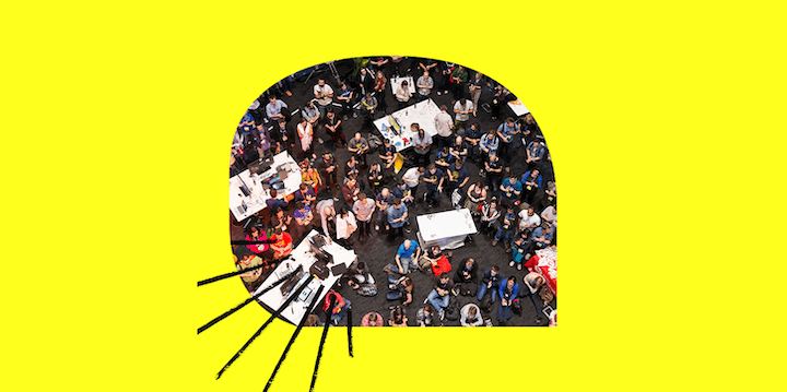 Yoğun bir kapalı etkinlik alanında toplanmış bir grup insan. Tepeden bakış.